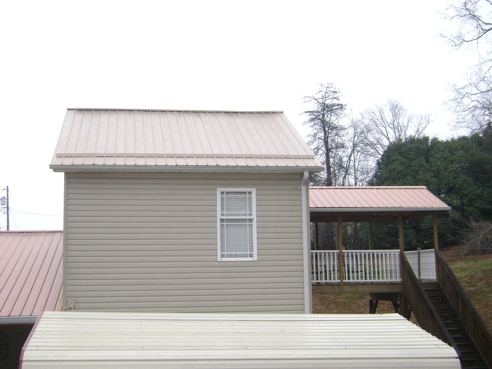 Tan metal roofs on a two story addition and attached porch, from a Roof Replacement job in New Market